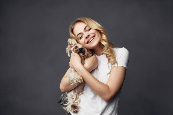 Blondine mit kleinem reinrassigen Hund joy smile dunkler Hintergrund - Foto, Bild