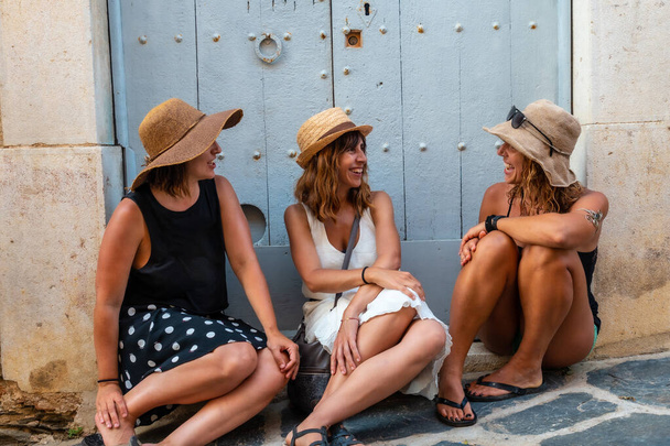Girlfriends in summer enjoying the holidays. Two sisters with a sister sitting on a wooden door enjoying the Mediterranean - Foto, imagen