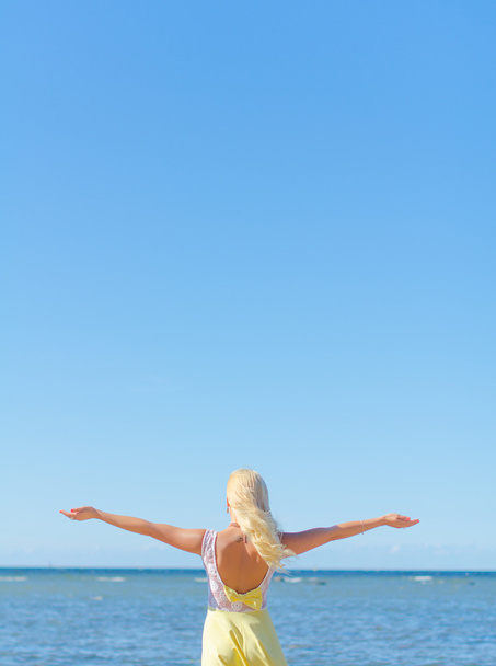 Mujer joven con los brazos abiertos cerca del mar. Lugar para el texto
. - Foto, imagen