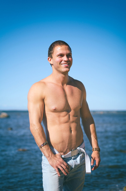 Muscular attractive man posing near the sea. - Valokuva, kuva