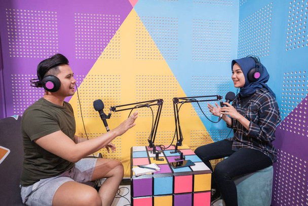 Muslimische Frau nimmt Podcast mit einem Mann im Studio auf - Foto, Bild