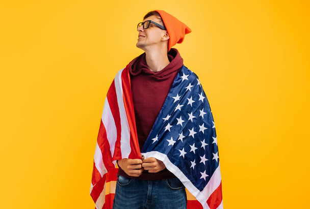 handsome man with an orange hat on his head with glasses and a red witer, holding moisture in his hands, 4th of july america day - Fotoğraf, Görsel