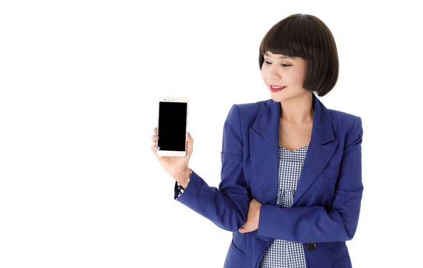 Souriant jeune femme d'affaires asiatique en tenue élégante montrant téléphone portable moderne avec écran noir vide sur fond blanc - Photo, image