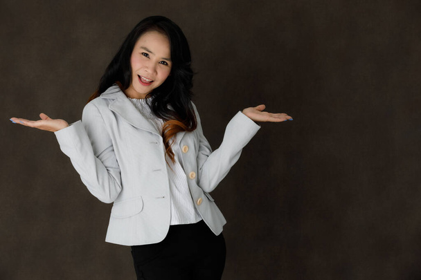 alegre joven asiático hembra en elegante formal ropa riendo felizmente mientras se divierten contra oscuro gris fondo - Foto, Imagen