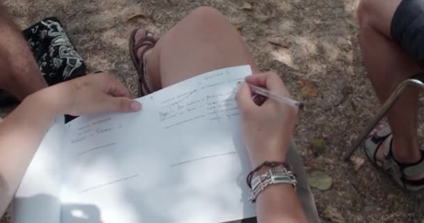 Νεαρή γυναίκα κάθεται στις καρέκλες της αίθουσας συνεδριάσεων και γράφει κάτι κρατώντας σημειώσεις σε χαρτί - Πλάνα, βίντεο