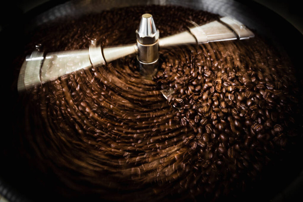 pražené spřádání chladič profesionální stroje a čerstvé hnědé kávová zrna pohyb zblízka tmavé fotografie v továrně Chiang rai Thajsko - Fotografie, Obrázek