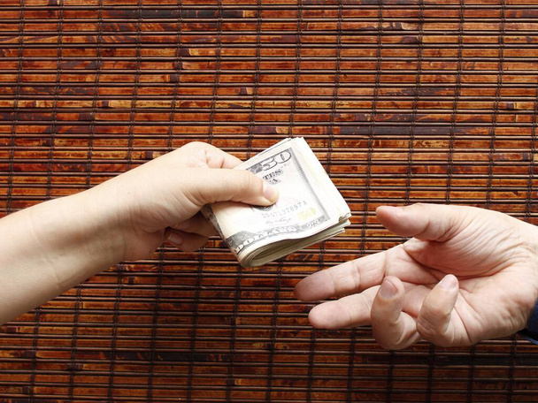 amerikai bankjegyeket átadó személy keze és egy másik átvevő személy keze - Fotó, kép