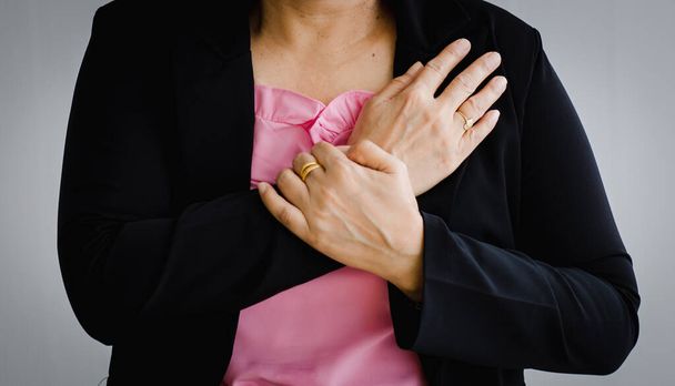 Nierozpoznana kobieta cierpiąca na nagły atak serca i trzymająca klatkę piersiową. Koncepcja opieki zdrowotnej w nagłych wypadkach i dotkniętych zastoinową niewydolnością lub reanimacją serca, problemy z sercem. - Zdjęcie, obraz