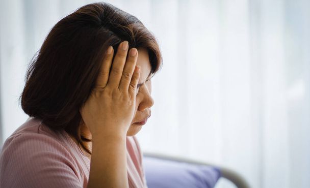 Middelbare leeftijd senior Aziatische vrouw voelt pijn van plotselinge hoofdpijn en herseninfarct en houdt haar hoofd met een gestresst gezicht. Concept van hersen- en hoofdprobleem. - Foto, afbeelding