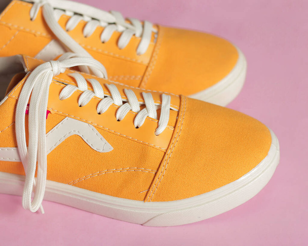 Las zapatillas de deporte conversas amarillas lisas aisladas sobre un fondo brillante son muy populares entre los adolescentes. Un modelo de zapato simple que es perfecto para la escuela o para la moda. Espacio libre para tu anuncio. maqueta del zapato. - Foto, Imagen