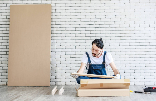 Jeune homme asiatique hipster travaillant comme bricoleur, assemblant une table en bois avec des équipements, concept de bricolage à domicile et self-service à la maison. - Photo, image