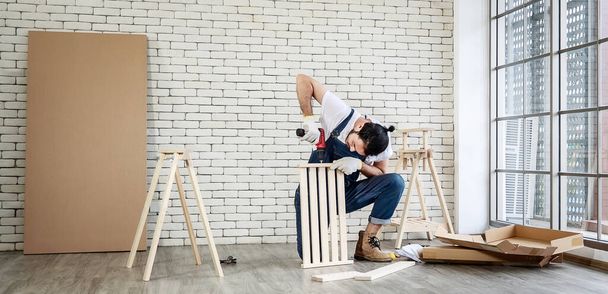 便利屋として働く若いアジアのヒップスター男性、家庭用機器と木のテーブルを組み立て、家の死とセルフサービスと趣味のための概念, - 写真・画像