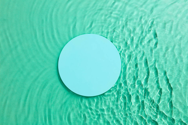 Empty Glass circle podium on transparent clear green water texture with splashes and waves in sunlight. Abstract nature background for product presentation. Flat lay cosmetic mockup. - Photo, image