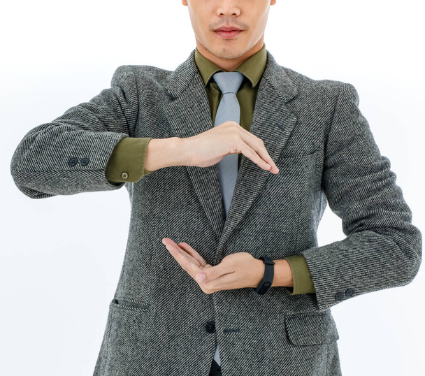Половина тела бизнесмен носит оливково-зеленую рубашку серый галстук темно-серый костюм руки сделать круговой узор на передней представляет собой символ синергии. Сила, комбинация понятий, белый фон - Фото, изображение