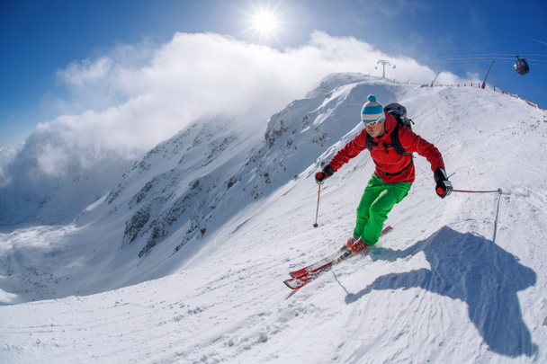 Skier skiing downhill in high mountains during sunny day - Photo, Image