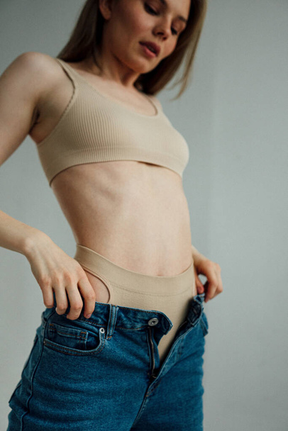 belle fille avec corps athlétique portant lingerie sportive et jeans posant en studio léger  - Photo, image