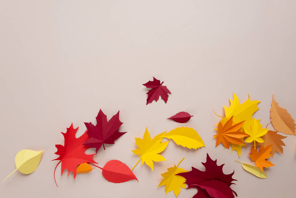 A frame made of autumn leaves on a beige background. The leaves are cut out of paper - 写真・画像