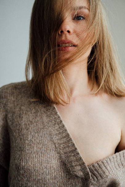 beautiful girl wearing warm sweater posing in light studio   - Foto, Imagen