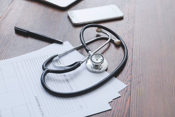 Stethoscope, documents, pen and mobile phone on wooden background - Photo, Image