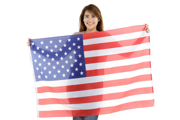 Photo de portrait isolé de belle jeune fille asiatique tenant tenant montrant grand drapeau national des États-Unis d'Amérique en arrière-plan blanc représentent la célébration le 4 Juillet jour de l'indépendance. - Photo, image