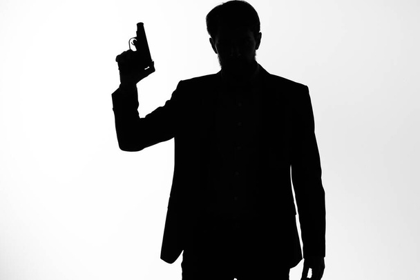 Ο άντρας με το κοστούμι Μυστικός πράκτορας με όπλο στα χέρια ενός εγκληματολογικού που παριστάνει το στούντιο. - Φωτογραφία, εικόνα