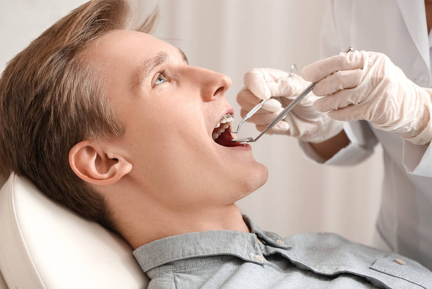 Homem bonito com aparelho dentário visitando ortodontista na clínica - Foto, Imagem