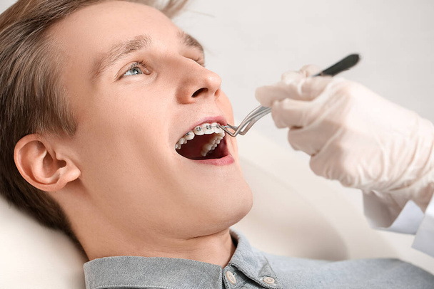 Handsome man with dental braces visiting orthodontist in clinic, closeup - Foto, afbeelding