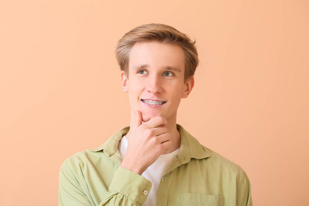 Красивый мужчина с зубными скобками на цветном фоне - Фото, изображение