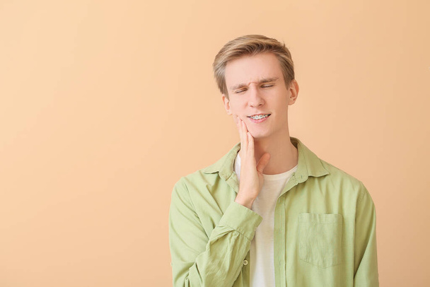 Jóképű férfi fogszabályzóval színes háttér - Fotó, kép