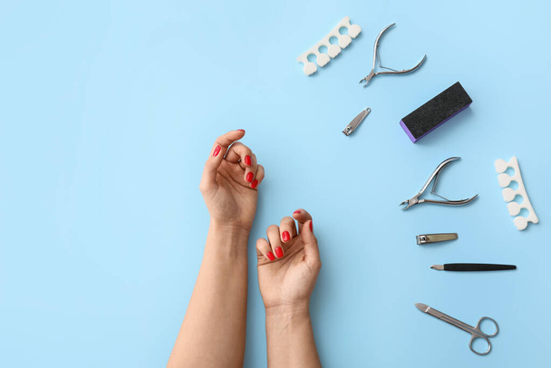 Female hands with tools for manicure on color background - 写真・画像