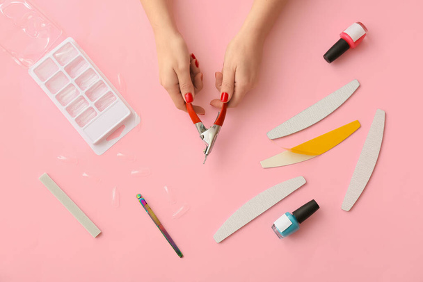 Mãos femininas com cortador de ponta e ferramentas para manicure sobre fundo de cor - Foto, Imagem