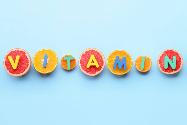 Text VITAMIN and citrus fruits on color background - Photo, Image