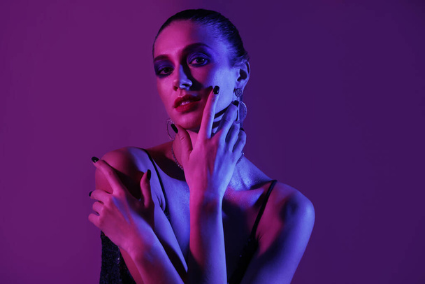 Mujer joven con estilo sobre fondo púrpura oscuro - Foto, Imagen