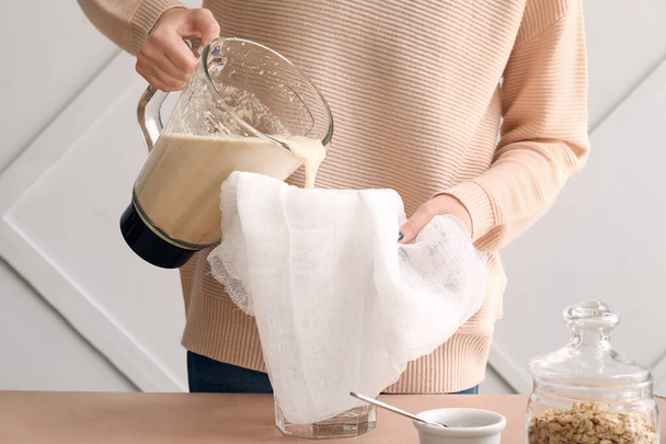 Mujer preparando sabrosa leche de avena en la mesa de la cocina, primer plano - Foto, imagen