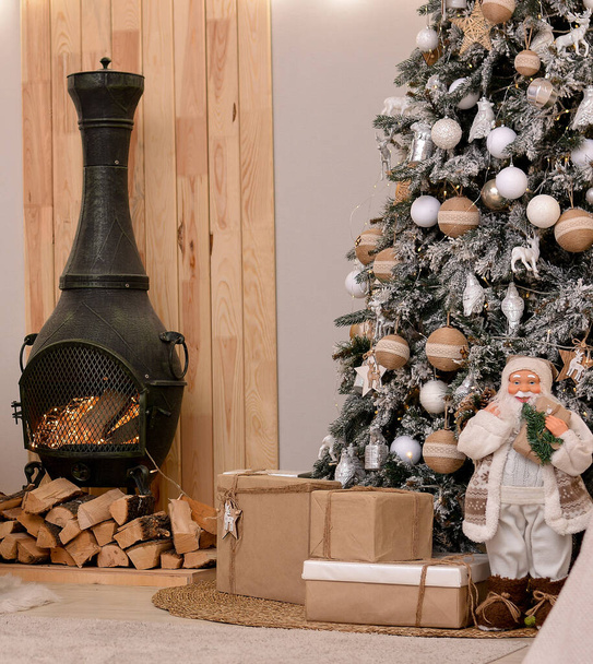 Weihnachtszimmer mit Weihnachtsbaum, Geschenkschachteln, Kamin, Brennholz, Weihnachtsmann-Spielzeug, Lichtern und Girlanden - Foto, Bild