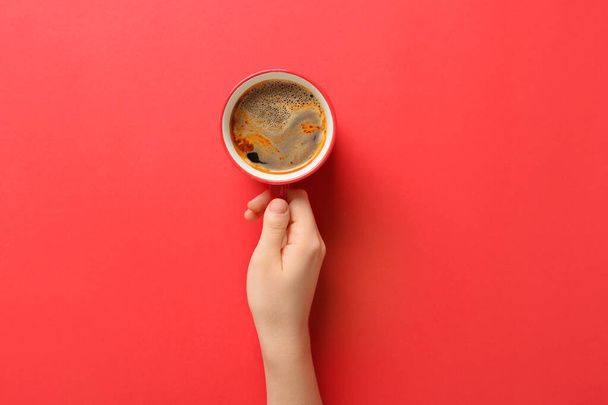 Mano femminile con tazza di caffè su sfondo rosso - Foto, immagini