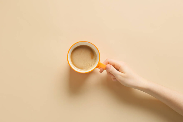 Female hand with cup of coffee on yellow background - Foto, afbeelding