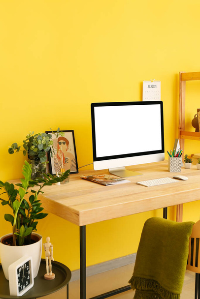Lugar de trabajo moderno con computadora y decoración cerca de la pared de color - Foto, Imagen