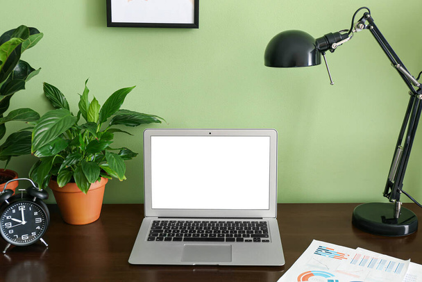 Σύγχρονη χώρο εργασίας με φορητό υπολογιστή κοντά σε πράσινο τοίχο - Φωτογραφία, εικόνα