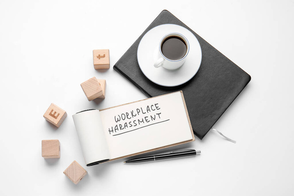 Notizbuch mit Text WORKPLACE HARASSMENT, Würfel und Tasse Kaffee auf weißem Hintergrund - Foto, Bild