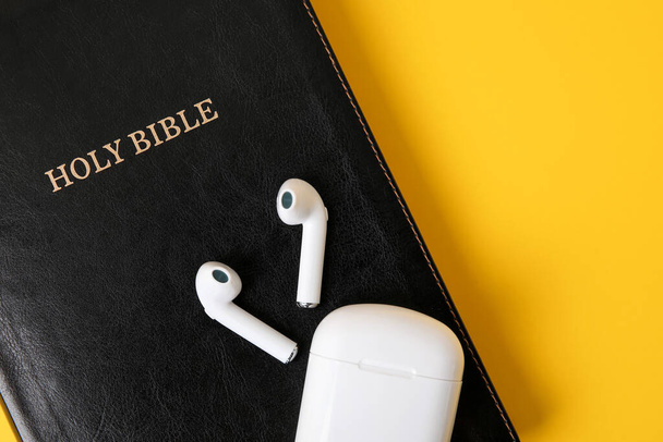Священна Біблія та навушники на кольоровому фоні крупним планом
 - Фото, зображення
