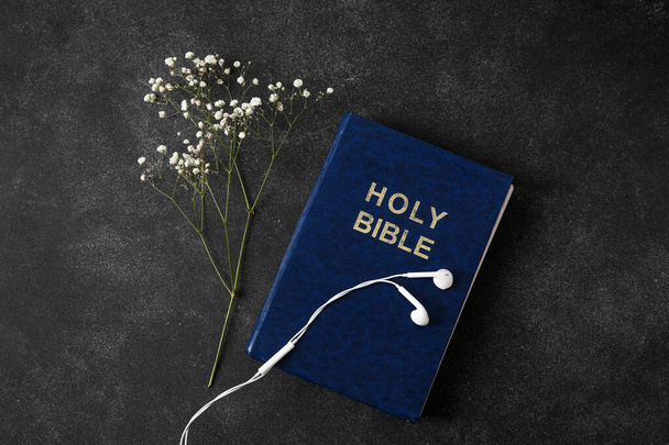 Kutsal İncil, çingene çiçekleri ve karanlık arka planda kulaklıklar. - Fotoğraf, Görsel