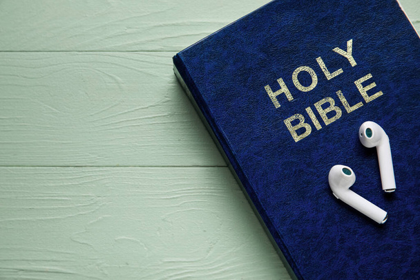 Santa Biblia y auriculares sobre fondo de madera de color, primer plano - Foto, imagen