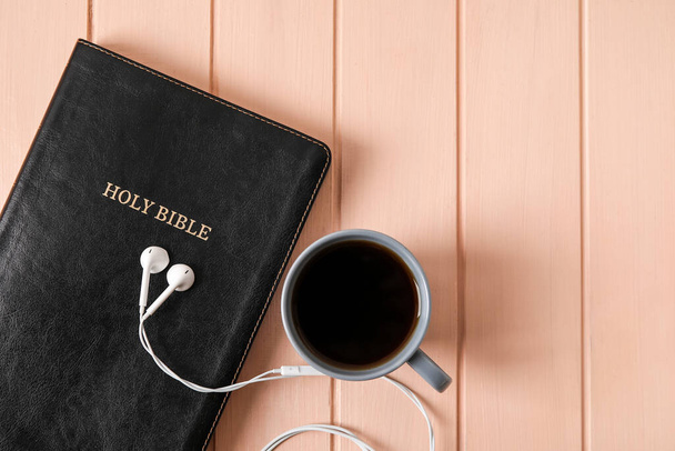 Santa Biblia, auriculares y taza de café sobre fondo de madera de color, primer plano - Foto, imagen