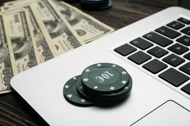 Poker chips with laptop on table in casino, closeup - Photo, Image