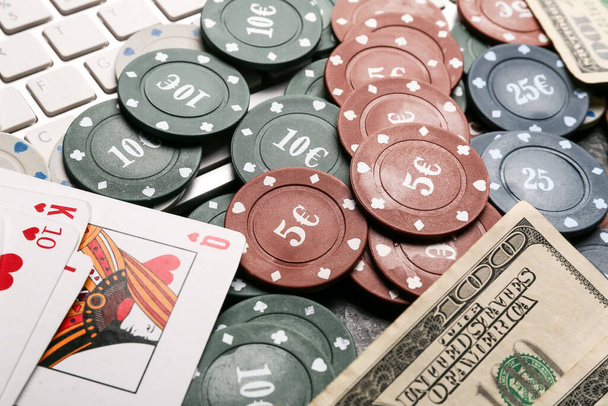 Покерні чіпи, доларові банкноти, гральні карти та комп'ютерна клавіатура на столі, крупним планом
 - Фото, зображення
