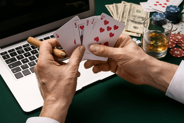 ラップトップを持つ男はカジノのテーブルでオンラインでポーカーをプレイ - 写真・画像