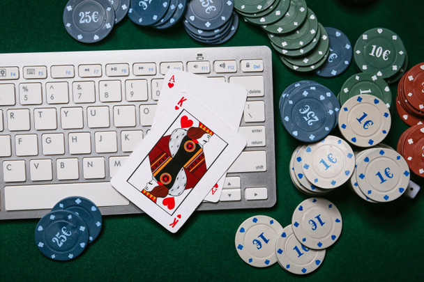 Computer keyboard, playing cards and poker chips on table in casino - Photo, Image