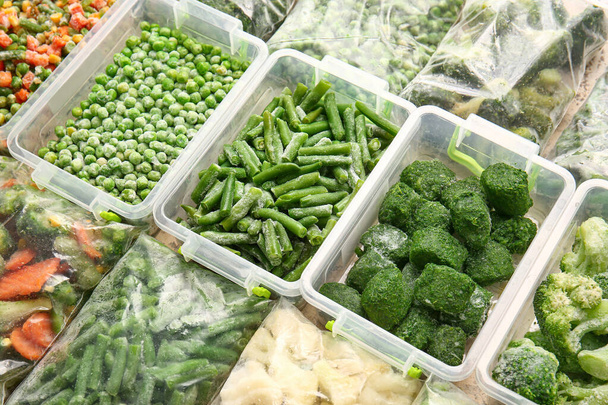 Sacs et contenants en plastique avec différents légumes congelés comme fond - Photo, image