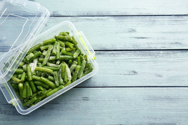 Plastic container with frozen green beans on color wooden background - Fotografie, Obrázek